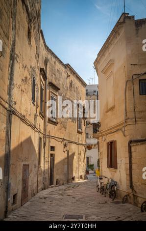 Zwei Fahrräder gegen eine Mauer in einem winzigen Innenhof, umgeben von Steinhäusern in der antiken Stadt Lecce, Apulien, Italien. Stockfoto