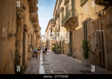 Eine Gruppe von Touristen in einer engen Straße gesäumt von Steinhäusern im Herzen der antiken Stadt Lecce, Apulien, Italien. Stockfoto