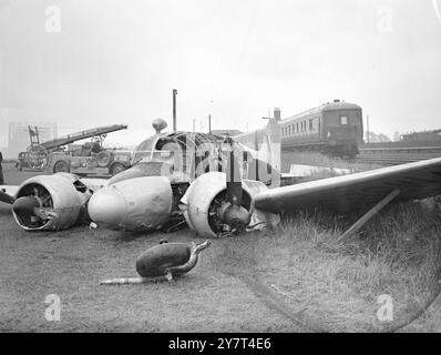 SECHS FLUCHTFLUGZEUGE STÜRZTEN AUF DER EISENBAHN alle sechs Insassen entkamen durch eine Hintertür, als die R.A.F Anson den Flughafen Portsmouth überschlug und heute auf die elektrifizierte Hauptstrecke zwischen Portsmouth und Havant stürzte. Der Port-Motor fing Feuer, und der Portsmouth Feuerwehrmann benutzte Schaumlöscher darauf. Der gesamte Bahnverkehr wurde aufgehalten, aber innerhalb von 2 Stunden hatte ein Pannenkran das Wrack von der Strecke geräumt. Ein Beamter des luftministeriums sagte, dass das Flugzeug, das von Ashton nach unten flog, Probleme mit der Bremse bei der Landung in Portsmouth hatte. DAS BILD ZEIGT:- die Feuerwehr steht (links) als erster Zug Stockfoto