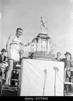 HOLDEN gewinnt ERNEUT WINDSOR CHISWICK-MARATHON Jack Holden von Tipton Harriers , der letztjährige Sieger der Veranstaltung , gewann erneut den Polytechnic Harriers Kinnaird Trophy-Marathon von Windsor nach Chiswick , London , als er in 2 Stunden 42 Minuten 52,4 Sekunden die Distanz von mehr als 26 Meilen zurücklegte . Eine Rekordzahl von 212 Wettbewerbern wurde von Prinzessin Elizabeth aus Windsor gestartet. DAS BILD ZEIGT:- JACK HOLDEN mit der Marathon-Trophäe nach dem Abschluss im Polytechnic Stadium in Chiswick, London . Juni 1949 Stockfoto