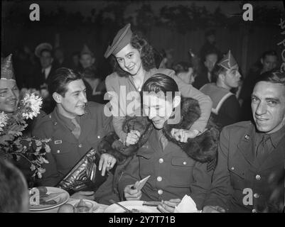 ALLIIERTE KAMPFMÄNNER AUS ZWEI WELTKRIEGEN IM BUCKINGHAM PALACE PARTY 1944 alliierte Kampfmänner, die in diesem Krieg verwundet wurden, und 1914-18 waren Gäste der „Not Forgotten“ Association bei einer großen Weihnachtsfeier in der Royal Riding School, Buckingham Palace. Die Herzogin von Kent war anwesend. FOTO ZEIGT: Miss Joan Crawford, die Tänzerin, zieht ihren Pelzmantel um Sergeant J. Tyner aus Tuscaloosa, Alabama, einen der amerikanischen Gäste. 21. Dezember 1944 Stockfoto