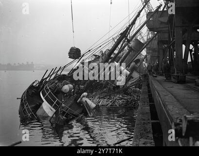 Der Belfast-Dampfer Dundrum Bay (1800 t) wird von der FRACHT ihrer Deck-FRACHT entlastet, die am nordwestlichen Quay in Tyne Dock, South Shields, ABGENOMMEN. Es wurden Versuche unternommen, das Schiff zu korrigieren, nachdem sie am Kai gesehen hatte. Die Dundrum-Bucht hatte begonnen, sich umzukippen, als Wasser wenige Stunden nach ihrer Ankunft mit einer Holzladung aus Deutschland in ihren Frachtraum eingedrungen war. 30. Dezember 1950 Stockfoto