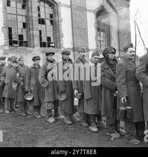 11. MÄRZ 1945Nearly 1.200 HUNGERNDE GEFANGENE wurden befreit, als die 7. US-Armee Stiring-Wendel südlich von Saarbrücken eroberte. Alle bis auf 200 bettseitige Männer gingen, krabbelten oder wurden in die amerikanischen Linien getragen, aber die ersten, die die Reise versuchten, wurden von zurückziehenden Deutschen erschossen. Diese Bilder wurden in einem Lager aufgenommen, wo sie gefüttert, medizinisch untersucht und registriert werden. Fotos zeigen: Einige der ausgemergelten Gefangenen, die vom 7. Befreit wurden. Armee, das sind Russen. Zerlumpt und ausgemergelt stellen sich die befreiten Gefangenen nach der Ankunft am Essen an Stockfoto