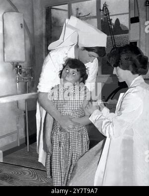 POLIO-IMPFUNG IN SOUTHAMPTON Southampton : die siebenjährige Maureen Doak von der Schule in Southampton sieht wehmütig aus, als sie ihre erste Impfung mit dem neuen Polio-Impfstoff von Dr. Catherine Atkins in der Sydney House Clinic in Southampton bekommt. Holding Maureen ist Krankenschwester Margaret Emery aus Highfield. 7. Mai 1956 Stockfoto