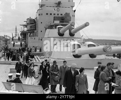 „Avantgarde“ bietet Besucher unter den mächtigen Geschützen des Schlachtschiffs, Urlauber - einer mit einem Warenkorb - besichtigen die Fichtendecks der „Vanguard“, Großbritanniens größtem Kriegsschiff, die während der Pfingstmarinetage in Plymouth der Öffentlichkeit gezeigt werden - einige der berühmtesten Schiffe der Royal Navy waren zu sehen. 28. Mai 1950 Stockfoto