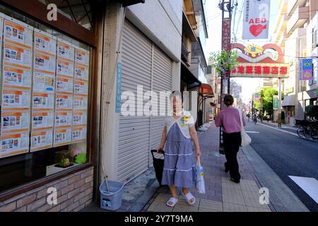 Ein älterer Käufer in der Sugamo Jizou-dori Einkaufsstraße mit dem Straßentor im Hintergrund. Toshima City. Tokio, Japan Stockfoto