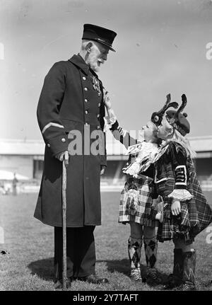 CURIOSITY AT THE SCOTS GAMES 13 Mai 1950 Chelsea-Rentner Thomas Watt, 78, beantwortet heute (Samstag) Fragen zu seinen Wahlkampfmedaillen der Tiny Scots Tänzer Doreen McInroy 7 (links) und Patricia Witts 7 im White City Stadium in London. Das Stadion ist der Schauplatz einer großen Versammlung von Schotten, die die London Caledonian Games veranstalten. Stockfoto