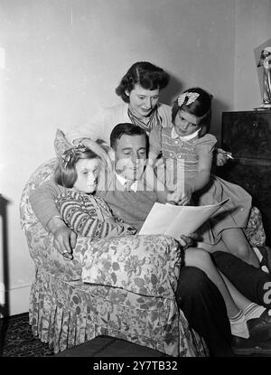 HOME IS THE HELD 30 April 1950 Reg Lewis, Held von Arsenals 2-Null-Sieg gegen Liverpool gestern im FA-Cup-Finale in Wembley, untersucht heute (Sonntag) Pressebilder des Spiels mit seinen achtjährigen Töchtern Anne (links) und Carol in ihrem Haus in Southgate, London. Im Hintergrund ist Mrs. Lewis. Der phänomenale Arsenal in Linke erzielte beide Tore seines Teams. Anne und Carol, die Zwillinge mit auburn, hörten die Exploits ihres Daddys auf dem Funkgerät. Stockfoto