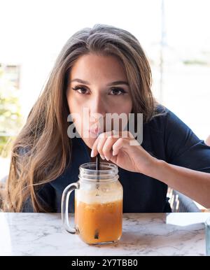Junge Frau trinkt Orangensaft Stockfoto