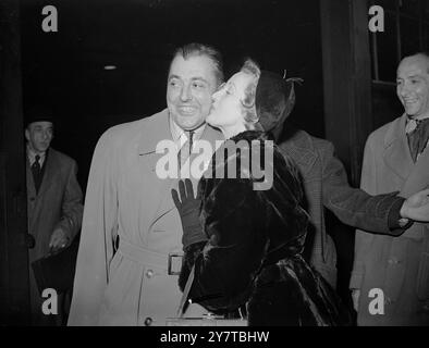 April 1950 Petite die britische Filmschauspielerin Anne Crawford musste auf Spitze stehen, um Jaques Tati, der mehr als 1,5m groß ist, einen Willkommenskuss zu geben, als der französische Komiker heute Abend (Montag) aus Paris in Victoria Station in London ankam. Tati namens Charles Chaplin, ist nach London gekommen, um morgen seinen Film Jour de Fete zu zeigen. Stockfoto