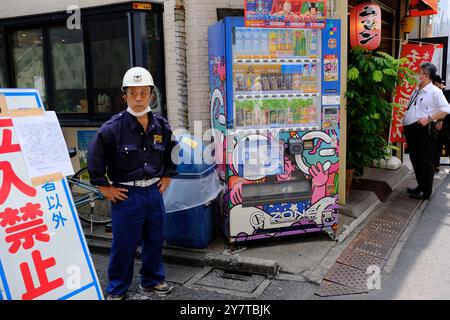 Ein uniformierter Arbeiter, der den Eingang einer Baustelle mit dem Schild „Don't Enter“ auf Japanisch in einer Seitenstraße von Harajuku bewacht. Tokio, Japan Stockfoto