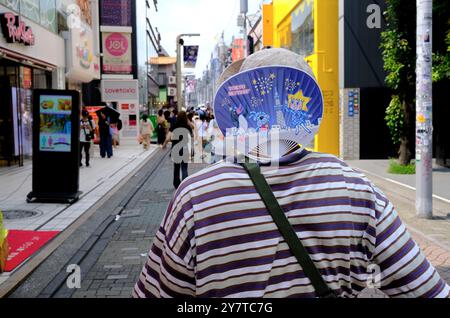 Ein Mann hat seinen Ventilator auf den Nacken gelegt. Takeshita Dori Straße. Harajuku, Shibuya. Tokio, Japan Stockfoto