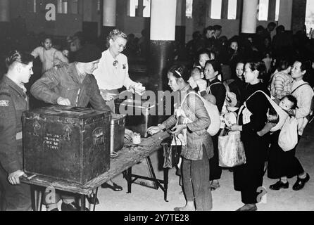 MÜTTER SCHLIESSEN SICH IN HONGKONG KINDERN Chinesische Mütter, Babys, die sich vom Rücken geschlagen haben, melden sich an, um ihr Essen zu bekommen - serviert von Freiwilligen der Armee - bei der jährlichen Kinderparty, die von der Hongkonger Gesellschaft zum Schutz der Kinder veranstaltet wird. Neben der Hilfe beim Essen nahmen Armeemänner Kinder mit für Jeep- und Ponyreiten. Fast 1.500 Mütter und Kinder erhielten eine warme Mahlzeit, Unterhaltung und Geschenke. 27. Februar 1950 Stockfoto