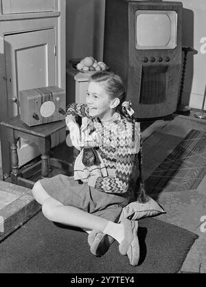 DIE 11-jährige Janette Scott, die HAUPTROLLE des Films ' No Place for Jennifer ', wird hier gezeigt, in der sie ihre französische Lieblingspuppe ' Janine ' hält und eine Sendung auf ihrem winzigen drahtlosen Set zu Hause in Leicester Mews, Lancaster Gate, London hört. Das Wireless-Set ist das günstigste Netzgerät in Europa und wird für 6/19/9T verkauft. Inklusive Einkaufssteuer. 12. Februar 1950 Stockfoto