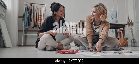 Zwei selbstbewusste Modedesignerinnen arbeiten zusammen in der Werkstatt Stockfoto