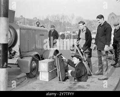 KAMERAMANN „PLUMBS THE DETHS“ 3. Februar 1950 der Auftrag mit einem ausgesprochen ungewöhnlichen Geschmack ging an KAMERAMANN Ian Struthers, der hohe Stiefel und einen Hut mit breiter Krempe trug und seine Kamera in die Tiefen der Londoner Kanalisation brachte. Struthers ging mit seinem Assistenten Michael Nunn in die tiefe Kanalisation vor der U-Bahn-Station Clapham North, um Dreharbeiten für den Film Spotlight Under London zu machen. Der Film wurde von Rayant Pictures of Wembley für die Serie „Spotllight Under London“ des 20. Jahrhunderts gedreht. DAS BILD ZEIGT: Ian Struthers geht in die Kanalisation von Clapham London und beobachtet Anthony Gilkison, den Direktor (in Stockfoto