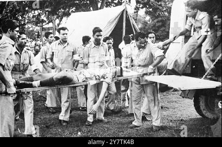 Indischer Polizist durch Bombe getötet - Pandit Nehru flüchtet knapp vor Attentat Kalkutta , Indien : Pandit Jawarharlal Nehru , der Premierminister von Indien, entkam knapp dem Attentat auf einem Massentreffen auf dem Calcutta Maidan. Als er das Rostrum aufnahm, wurde eine Bombe 100 Meter entfernt an einem Punkt geworfen, an dem das Auto einen Moment zuvor vorbeigefahren war. Ein Polizist wurde getötet und fünf verletzt. Zwei Männer wurden verhaftet. Nachdem Herr Nehru den Maidan verlassen hatte, wurden zwei nicht explodierte Bomben in der Nähe des Rostrums gefunden. Foto zeigt: Gour Singh, ein Garhwali-Konstabler des 3. Bataillons, Westbengalen Armed Police, wird hochgehoben Stockfoto