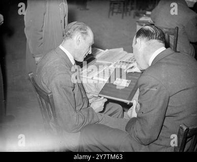 Hitler-Untergang-Briefmarken an der International Bourse in London Händler aus vielen Ländern nehmen an der International Stamp Trade Bourse Teil , die in der Central Hall in Westminster eröffnet wurde . Foto-Shows: Herr L Klein aus Österreich (links) und Herr C Taylor aus Großbritannien prüfen einen besonderen Satz von Briefmarken, die kürzlich in Österreich zum Gedenken an den Untergang Hitlers am 30. September 1946 ausgestellt wurden Stockfoto