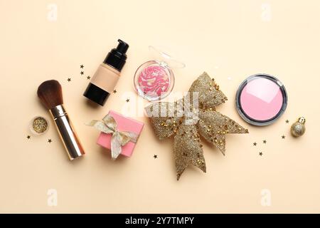 Flache Komposition mit Make-up-Produkten und Weihnachtsdekor auf beigefarbenem Hintergrund Stockfoto