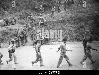 IN KOREASomewhere in Korea: Während sich die Truppen der US-Armee auf Frontpositionen an der koreanischen Schlachtfront bewegen, marschiert der Infanterie der sich zurückziehenden Südkoreanischen Armee (im Vordergrund) auf ihrem Weg zu den hinteren Positionen vorbei. Die beiden Männer davor scheinen keine Verteidigungswaffen oder Ausrüstung zu haben. 14. Juli 1950 Stockfoto