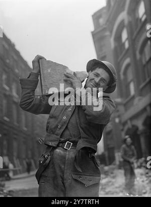 Das Foto zeigt: Ein typisches Mitglied des Auxiliary Military Pioneer Corps, das fröhlich einen Klumpen Mauerwerk schultert, während er dabei hilft, Luftschutt in London zu beseitigen. 29. Oktober 1940 Stockfoto