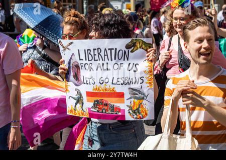 Befreiung für uns alle. Lass uns Lesben gehen. Frau mit Papierschild bei der Helsinki Pride 2024 Parade auf der Mannerheimintie in Helsinki, Finnland. Stockfoto