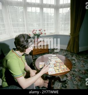 Junge Frau, die Solitär in ihrem Wohnzimmer spielt, England. Um die 1970er Jahre Stockfoto