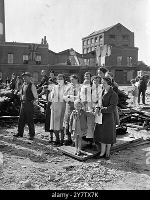 EAST LONDON FEIERT DEN ZWEITEN JAHRESTAG DER SCHLACHT UM GROSSBRITANNIEN anlässlich des zweiten Jahrestages der Schlacht um Großbritannien nahmen die Menschen von Stepney, einem sehr stark verwüsteten Gebiet im East End von London, an einem Gottesdienst Teil, den ihr Rektor, Reverend Reginald French, in den Ruinen einer geschossenen Schule im Bezirk durchgeführt hatte, um dem Mut der RAF-Männer zu gedenken, die London in der Schlacht um Großbritannien verteidigten. Frauen und Kinder hören sich den Gottesdienst an, der vor der geschädigten Schule in Stepney stattfindet. 15. September 1942 Stockfoto