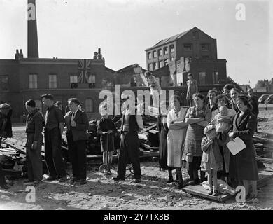 EAST LONDON FEIERT DEN ZWEITEN JAHRESTAG DER SCHLACHT UM GROSSBRITANNIEN anlässlich des zweiten Jahrestages der Schlacht um Großbritannien nahmen die Menschen von Stepney, einem sehr stark verwüsteten Gebiet im East End von London, an einem Gottesdienst Teil, den ihr Rektor, Reverend Reginald French, in den Ruinen einer geschossenen Schule im Bezirk durchgeführt hatte, um dem Mut der RAF-Männer zu gedenken, die London in der Schlacht um Großbritannien verteidigten. Frauen und Kinder hören sich den Gottesdienst an, der vor der geschädigten Schule in Stepney stattfindet. 15. September 1942 Stockfoto