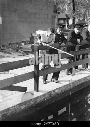 FISCHE IN LONDONER FEUERWEHRTANKS GEFUNDEN drei große Karpfen wurden in einem ARP-Notwassertank am Leicester Square, London, gefunden, obwohl ihre Anwesenheit ein vollständiges Rätsel ist. Die Polizei glaubt, dass sie von einem praktischen Witz dorthin gebracht wurden. Foto zeigt: Der 12-jährige Gerald Hide of Hastings, der in London Urlaub macht und ein Stück Rohr als Rute benutzt, während er im Wassertank am Leicester Square fischt, in der Hoffnung, einen Teil des Karpfens zu fangen, beobachtet von Männern der National Fire Service. 16. September 1942 Stockfoto