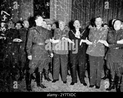 Zusammen mit den Händen, um Auld lang Syne im Mansion House zu singen, sind Londons Lord Mayor, Alderman Cuthbert Ackroyd (Mitte) und Tänzer des sowjetischen Armeeensembles. Auf der rechten Seite des Oberbürgermeisters befindet sich der Leiter des Ensembles Oberst Boris Alexandrow und im Vordergrund der Solist Arthur Eisen. Alderman Ackroyd hatte eine Gruppe von 200 Mitgliedern des Ensembles organisiert, die derzeit in der Londoner Empress Hall auftreten, um das Mansion House zu besuchen. Die Uniform wurde am 5. Juli 1956 getragen Stockfoto