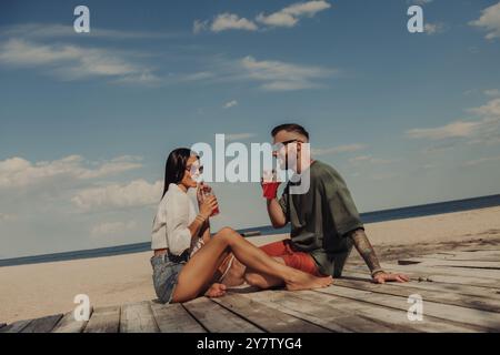 Junges romantisches Paar, das erfrischende Cocktails genießt und sich am Strand entspannt Stockfoto
