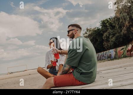 Wunderschönes Paar, das Cocktails und Meerblick genießt und sich am Strand entspannt Stockfoto