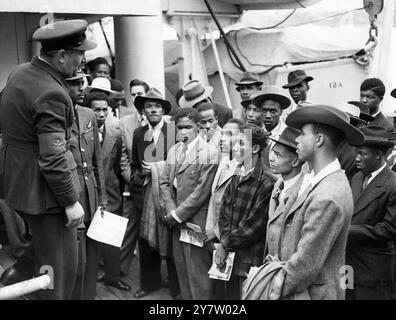 Ankunft an Bord des ehemaligen Truppenschiffs HMT Empire Windrush in Tilbury. Ein RAF-Rekrutierungsoffizier spricht mit einer Gruppe von Männern, die an der Royal Air Force interessiert sind. 22. Juni 1948 Stockfoto