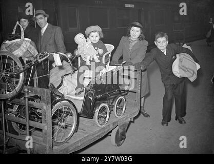 EVACU „EASE“ 7. Dezember 1940 Foto zeigt: Ein kleiner Evakuierter, der gerade einen Londoner Bahnhof aus einem Sicherheitsbereich verlassen will, der auf einem kleinen Stuhl auf einem Rollwagen sitzt, der auf dem Weg zum Zug vor der Abfahrt auf einem Wagen abgestellt wurde Stockfoto