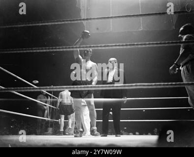 WOODCOCK BESIEGT MILLS MIT PUNKTEN BEI HARRINGAY Bruce Woodcock, der britische Schwergewichtsmeister, besiegte Freddie Mills, den Titelträger des Cruiserweight-Titels, in einem zwölf-Runden-Wettbewerb in der Harringay Arena in London. Foto zeigt: Moss Doyong, der Schiedsrichter, hält Woodcocks Hand hoch und erklärt ihn am Ende des Kampfes zum Sieger. 4. Juni 1946 Stockfoto