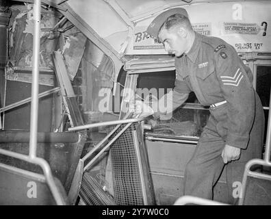 LONDONER STURM ENTWURZELT STRASSENSPERREN - VERURSACHT BUSSTÜRZE IN DEN LADEN - 13 MENSCHEN VERLETZT. Der schreckliche Sturm über London führte dazu, dass Straßensperren in der Kensington High Street entwurzelt wurden. Ein Bus von 49 rutschte auf den entwurzelten Straßenblöcken und stürzte in ein Schaufenster. 13 Menschen wurden verletzt und mit 3 schwer ins Krankenhaus gebracht. Fotoshows: Sergeant J C Meldrum RASC aus Ilford, der einen Krankenwagen der Armee rief und half, die Verletzten aus dem Bus zu holen, sah man, wie er den Damm auf dem Oberdeck des abgestürzten Busses untersucht. 26. Juli 1946 Stockfoto