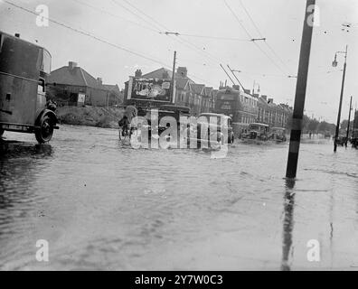 'AMPHIBIEN' LONDONS ÜBERSCHWEMMEN, ALS TROPISCHER STURM DIE HAUPTSTADT TRIFFT. Ein gigantisches Gewitter, das über Großbritannien brach, brachte sintflutartige Regenfälle nach london, überflutete Straßen und Bahngleise und stürzte die Verkehrsdienste ins Chaos. Fotoshows: Verkehr, der durch tiefes Hochwasser an der Kreuzung von Lea Bridge Road und Eastern Road, Whipps Cross, in der Nähe von London fließt. 27. Juli 1946 Stockfoto