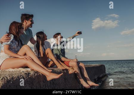 Gruppe fröhlicher Freunde, die Selfie machen und lächeln, während sie unbeschwerte Zeit am Meer genießen Stockfoto