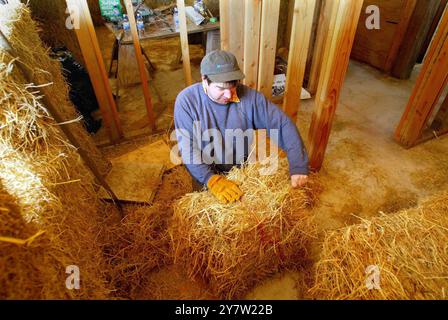 Cazadero, Kalifornien-James Yates aus San Francisco, Kalifornien, stapelt am Sonntag, den 28. April 2002, in den Wänden eines Badezimmers eines traditionellen Cotswaldhauses aus Strohballen Strohballen. Strohballen werden für den Bau eines ansonsten traditionellen Cotswaldhauses verwendet, das in den Hügeln des Sonoma County hinaufgeht. Das Haus mit zwei Schlafzimmern und zwei Badezimmern, das für James Yates gebaut wird, verfügt über Reistrohballen, die auf der Außenseite des Hauses gestapelt und dann mit einer dicken Schicht Gipskement beschichtet sind. Häuser mit Strohballen-Komponenten sind bei Menschen, die suchen, immer beliebter geworden Stockfoto