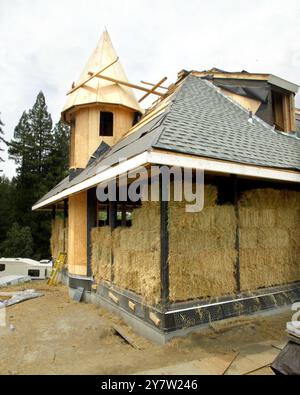 Cazadero, Kalifornien - Strohballen werden für den Bau eines ansonsten traditionellen Cotswald Cottages verwendet, das in den Hügeln des Sonoma County hinaufgeht. Das Haus mit zwei Schlafzimmern und zwei Badezimmern, das für James Yates aus San Francisco gebaut wird, verfügt über Reistrohballen, die auf der Außenseite des Hauses gestapelt und dann mit einer dicken Schicht Gipskement beschichtet sind. Häuser mit Strohballen-Komponenten werden immer beliebter bei Menschen, die nach erschwinglichem Wohnraum und Luxus suchen. Foto am Sonntag, 28. April 2002. Stockfoto