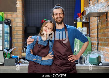 Ein paar Kollegen zu umarmen, Partner junger Mann und Frau in Schürzen am Arbeitsplatz Stockfoto