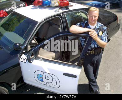 Capitola, Kalifornien: Offizier Andrew Dally vom Capitola Police Department steht am Montag, den 6. August 2001 neben seinem Streifenwagen und trägt seine optionale Sommeruniform, ein Hawaiin-Hemd mit Abzeichen-Nummer. Die Idee ist, die Polizei zugänglicher zu machen. Viele Einwohner von Capitola pendeln zu ihren Jobs im Silicon Valley. Stockfoto