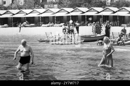 Winston Churchill und seine Frau, die hier Urlaub machen, gehen im Lido von Venedig, Italien, schwimmen. Mrs. Churchill trägt ein langes Kostüm, während ihr Mann rote Badehosen trägt. Mr. Churchill widersprach, dass Fotografen ihn in seinen roten Kofferräumen vorstellten, und ließ die Wärter ihre Filme ergreifen. Irgendwann spritzte der Ex-Premier, der die französische Riviera verließ, weil es zu laut war, Wasser auf Kameramänner, als sie sich ihm in einem Boot näherten. 2. September 1951 Stockfoto