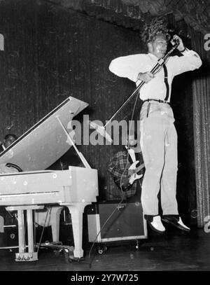 Jerry Lee Lewis hüpft mit einem mike, Rock and Roll und lässt seine eigenen Haare während seiner Eröffnungsaufführung im Cafe de Paris in New York, USA, stehen. Sein verwirrter Familienstand hat ihn letzten Monat aus Großbritannien gepackt, was ihn zwang, eine Tournee 37 abzusagen. Er hat nun seine 13-jährige Braut wieder geheiratet, um „die Menschen in den USA und England zu befriedigen“, dass alles legal war.12. Juni 1958 Stockfoto