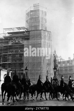 Während Londons berühmte „Horseguards“ heute in Whitehall ankommen, wird für die Zeremonie des Wachwechsels das war Office Building (im Hintergrund) einem Reinigungsversuch unterzogen. Das Gebäude, das in einem Polyethylen-Kokon untergebracht ist, wird von London Stone gereinigt und bemalt, der Nelson's Column gereinigt hat. Sie experimentieren mit der Reinigung der Fassade öffentlicher Gebäude bei jedem Wetter, um zu beweisen, dass Außenpflegearbeiten in den Wintermonaten in London, England, durchgeführt werden können.29. Januar 1969 Stockfoto