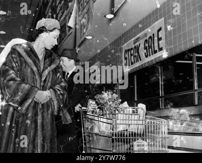 Queen Elizabeth sieht sich die Einkäufe einer Käuferin an, während sie einen amerikanischen Supermarkt besucht. Mit Prinz Philip fuhr die Königin von einem American Football-Spiel zurück, als sie den überraschenden Besuch im Laden abstattete. Sie und der Prinz spazierten 15 Minuten lang herum und unterhielten sich mit Verkäufern und Käufern aus Washington USA. (American Football Match fand am 18. Oktober 1957 statt) 20. Oktober 1957 Stockfoto