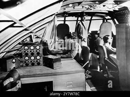 Howard Hughes hat gerade ein riesiges Flugboot auf Terminal Island im Hafen von Los Angeles gebaut. Es wartet jetzt auf Taxt-Tests in den Hafengewässern. Fotoshow: Das vordere fliegende Deck des Hughes Flying Boat. Links ist der Funkbetreiber, in der Mitte ist Howard Hughes, der Flugzeughersteller, und rechts der Flugingenieur und sein Labyrinth aus Bedienelementen und Messgeräten. Beachten Sie die Rückseite der beiden Pilotensitze im Hintergrund. 3. November 1947 Stockfoto