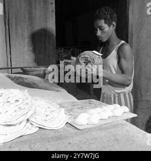 Katar - 1954 Aufbau von Kapatten in einer Bäckerei in Khor , einer kleinen Küstenstadt 25 Meilen nördlich von Doha . Die Teigrollen werden flach gegen einen Stoffbeutel geschlagen und zum Backen auf die Seiten des Ofens gelegt . Stockfoto