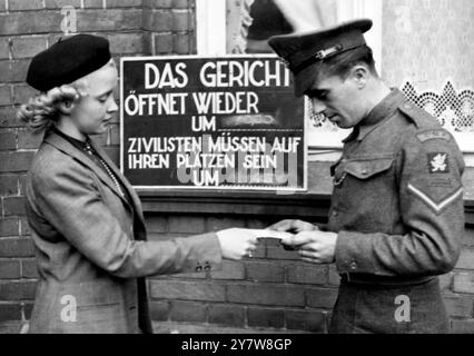 Sicherheitskontrollen im Belsener TrialLuneberg , Deutschland : Lance-Corporal T. Webb aus Willesden , London , überprüft den Pass eines nicht identifizierten Zivilisten vor dem Gerichtssaal hier im Rahmen des ersten Kriegsverbrecherprozesses . 19. September 1945 Stockfoto